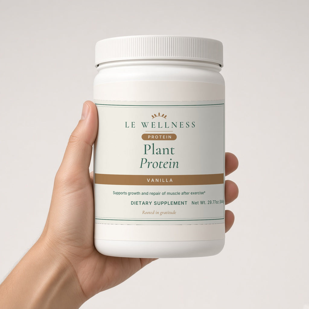 Hand holding Le Wellness Plant Protein (Vanilla) tub